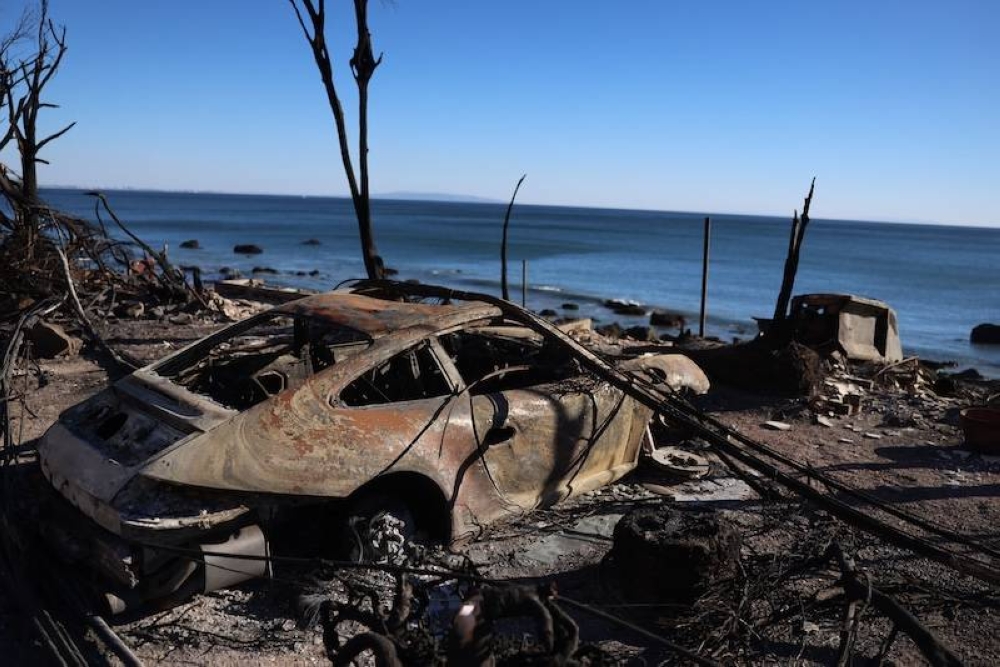 Un vehículo carbonizado aparece a lo largo de la Pacific Coast Highway en Malibú, California, mientras el incendio Palisades sigue creciendo el 12 de enero de 2025. Las autoridades estadounidenses advirtieron que los vientos 