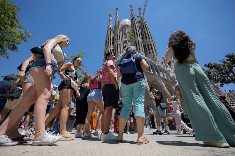 Turistas caminan frente a la basílica de la Sagrada Familia en Barcelona,  España./ AFP