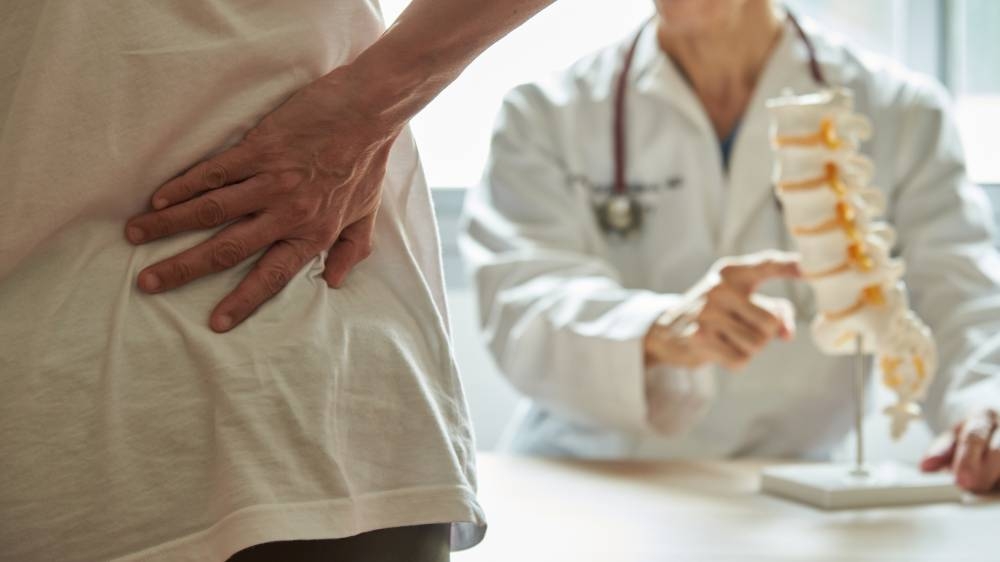 La recuperación para los dolores de espalda pueden incluir fisioterapia. /DEM ,image_description:A doctor explaining lumbar anatomy to back pain patient