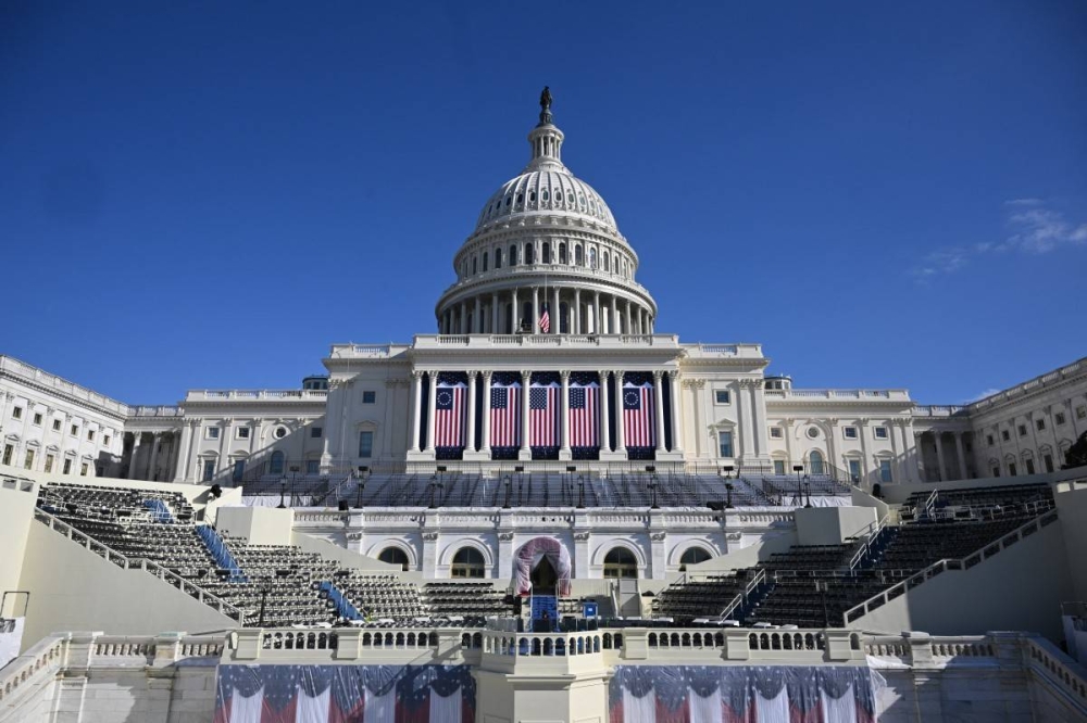 Banderas estadounidenses ondean en el frente oeste del Capitolio de Estados Unidos, donde tradicionalmente se lleva a cabo la investidura presidencial, el 17 de enero de 2025, en Washington, DC. /AFP,image_description: