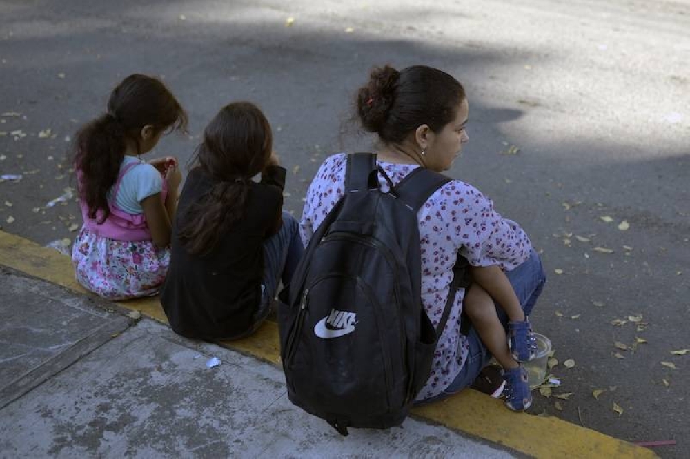 Una mujer migrante hondureña, con tres hijos, espera afuera de la oficina regional del Instituto Nacional de Migración para esperar su salvoconducto para transitar por territorio mexicano en su camino a Estados Unidos, en Tapachula, estado de Chiapas, México. / AFP