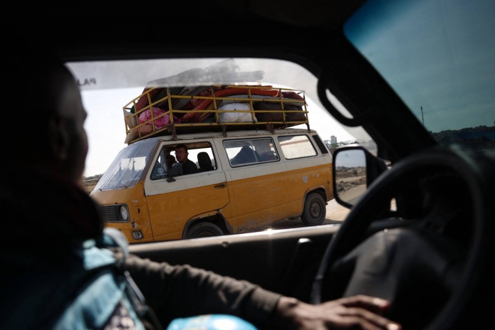 Un conductor mira desde la ventanilla de su coche a la gente que regresa con sus pertenencias a Nuseirat, en el centro de la Franja de Gaza, el 19 de enero de 2025, poco antes de que se aplicara un acuerdo de alto el fuego en la guerra entre Israel y el grupo militante palestino Hamás. (Foto de Bashar TALEB / AFP)