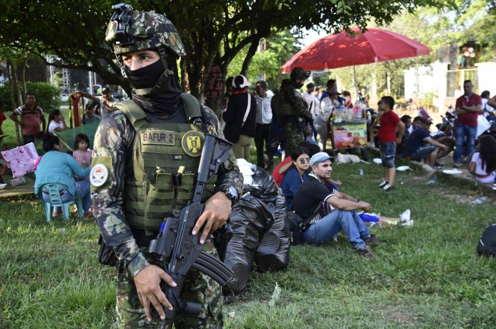 Soldados del ejército colombiano hacen guardia junto a personas desplazadas por los recientes enfrentamientos entre grupos armados que llegaron al municipio de Tibú, departamento de Norte de Santander, Colombia, el 18 de enero de 2025. (Foto de Schneyder Mendoza / AFP)