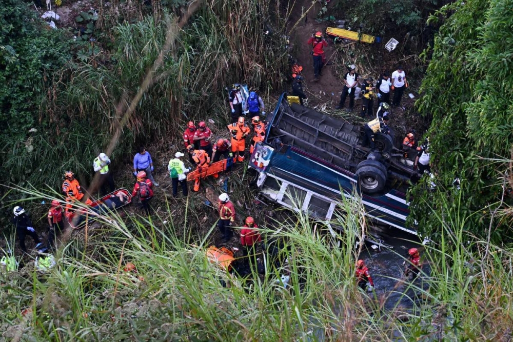 Bomberos y policías trabajan en el lugar de un accidente en el que un autobús cayó por un barranco en la Ciudad de Guatemala el 10 de febrero de 2025. JOHAN ORDÓNEZ /AFP,image_description: