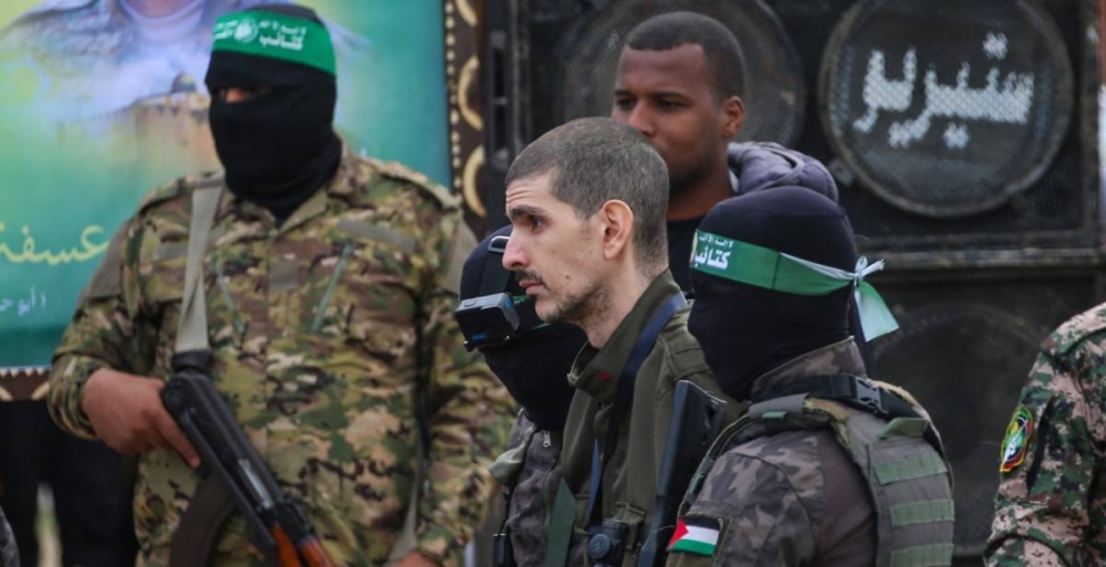 Combatientes palestinos de Hamas escoltan al rehén israelí Or Levy en un escenario antes de entregarlo a un equipo de la Cruz Roja en Deir elBalah, en el centro de Gaza/ Foto Eyad Baba AFP.,image_description: